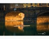 two early riser canoeists under the ponte santa trinita in florence